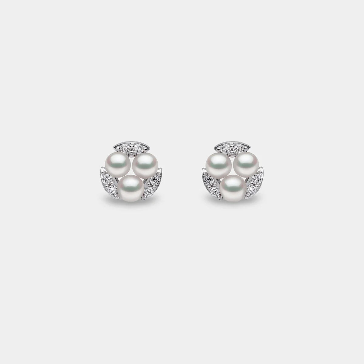 White gold triple pearl and diamond stud earrings on grey background, front view
