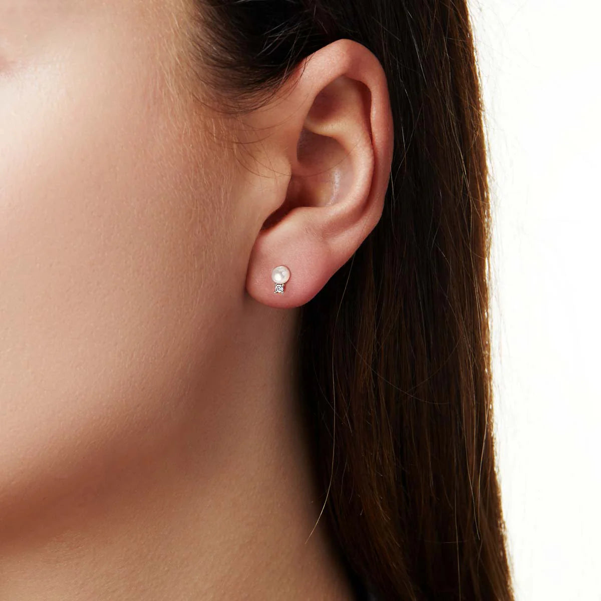Woman wearing white pearl stud earrings with diamond accents