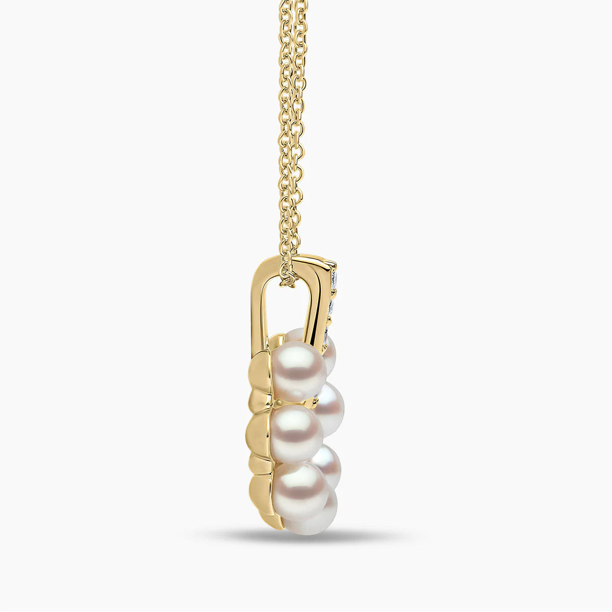 Yellow gold pearl pendant with diamond accents on grey background, side view