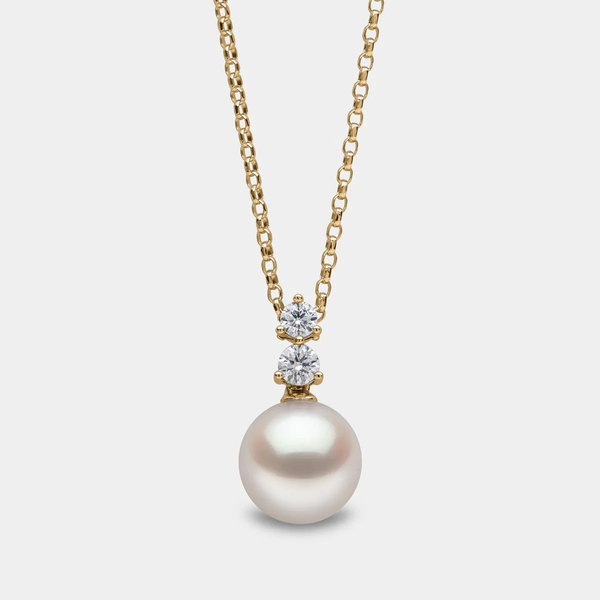 Yellow gold pearl pendant with two diamond accents on grey background, front view