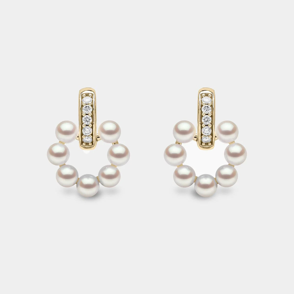 Yellow gold pearl and diamond stud earrings on grey background, front angle view