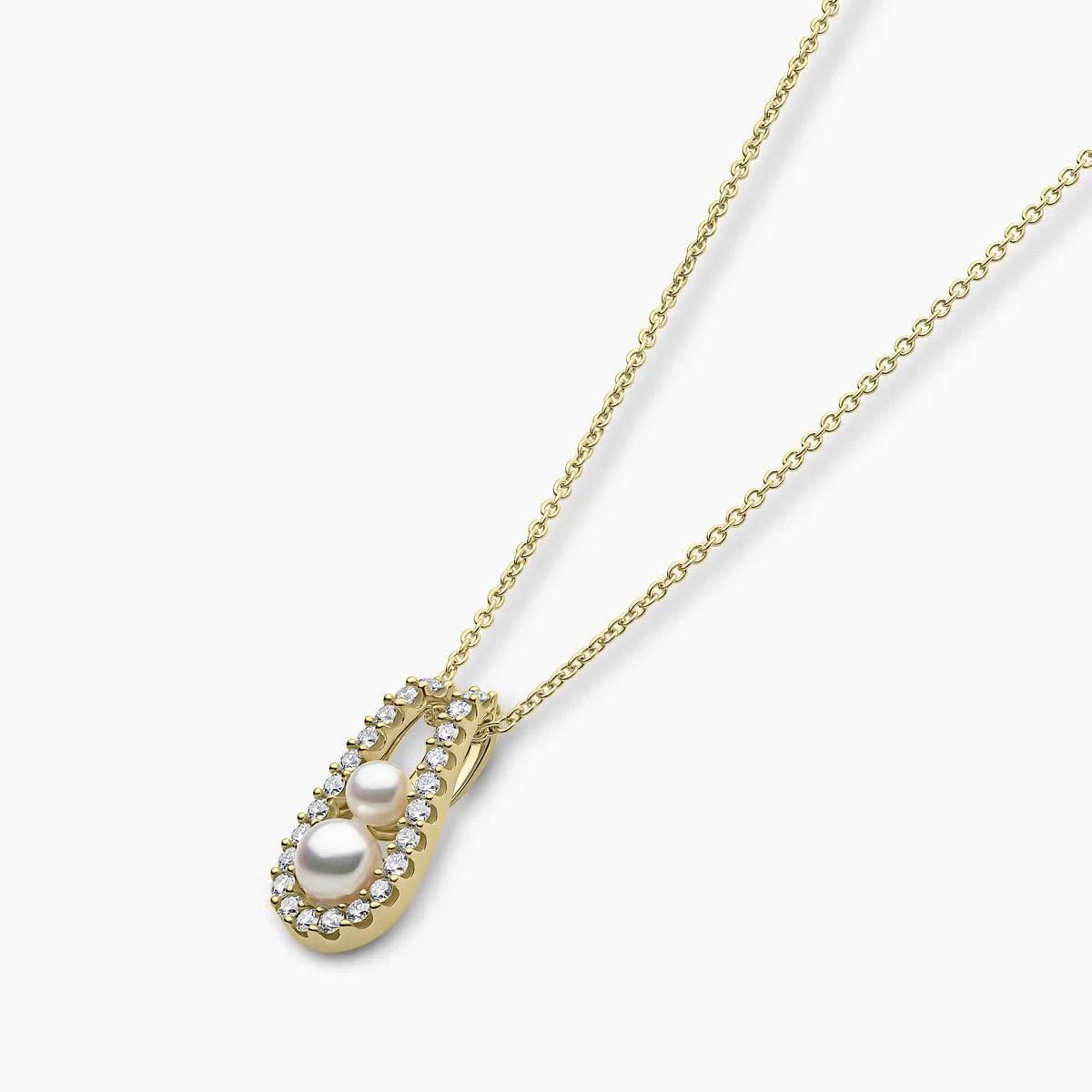 Yellow gold pearl and diamond pendant necklace on grey background, side angle view