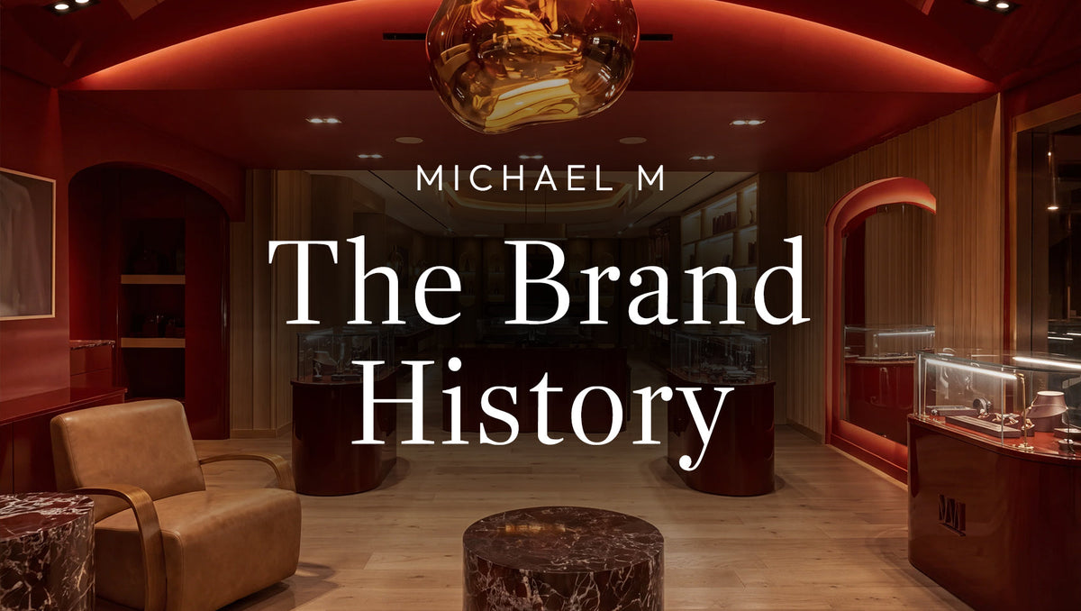 nterior of the MICHAEL M jewelry boutique featuring warm wood finishes, red accents, and jewelry display cases, with the text “MICHAEL M The Brand History” overlaid.
