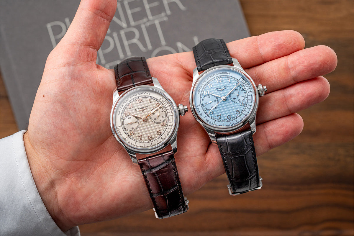 Two Longines Master Collection Chrono Monopusher watches with ivory and blue dials held side by side