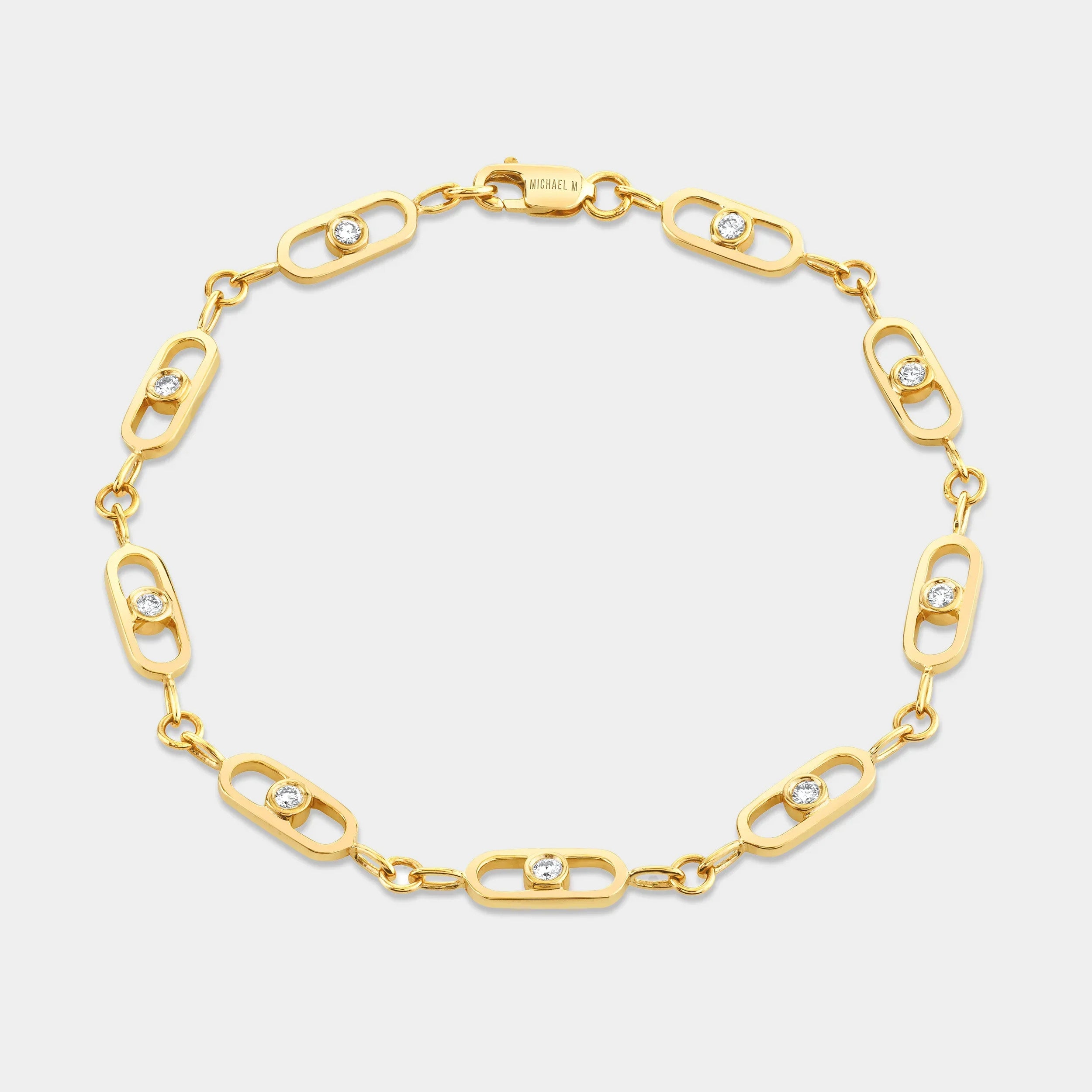 Yellow gold paperclip link bracelet with bezel set diamonds on grey background, flat lay view