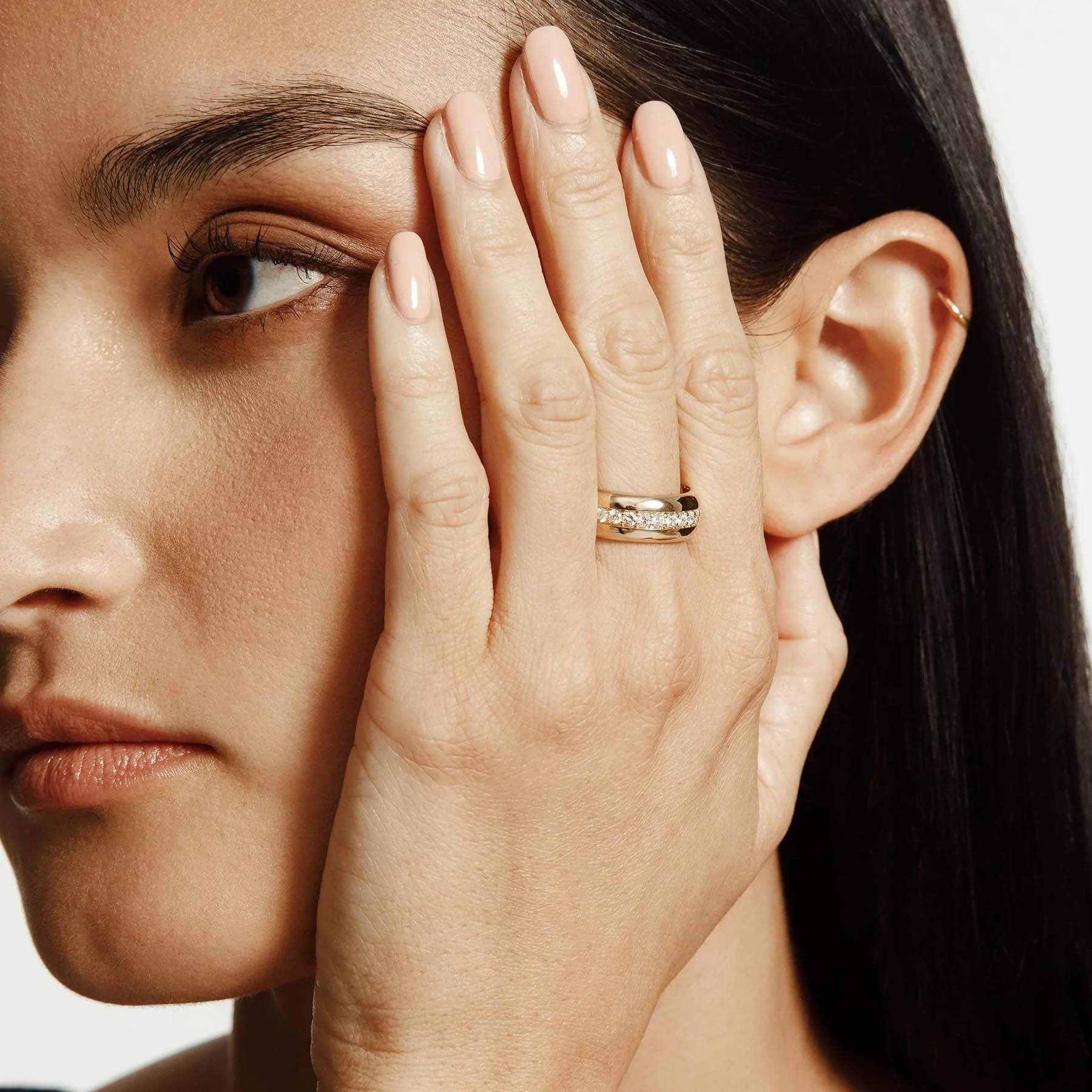 Woman wearing yellow gold fashion ring with diamond center row
