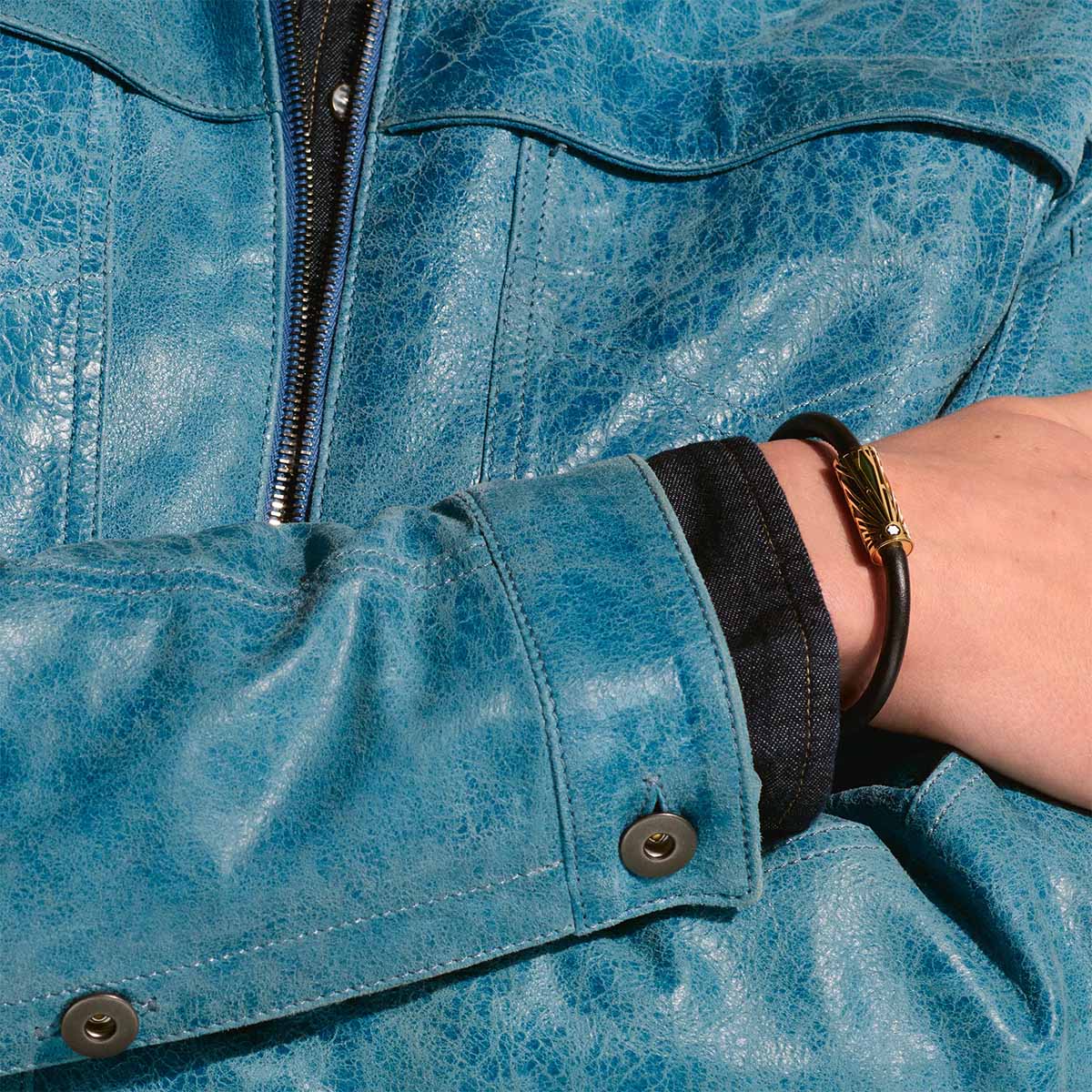 Man wearing Montblanc Meisterstück Origin black leather bracelet with gold-tone stainless steel clasp featuring green lacquer detailing and Montblanc emblem
