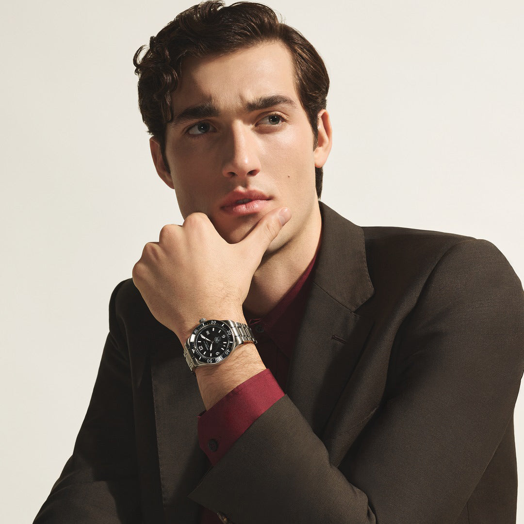 Man wearing a watch with a neutral background