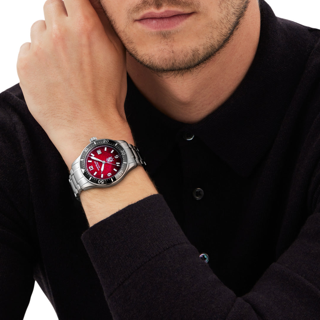 Man wearing a watch with a red face and silver case on a white background