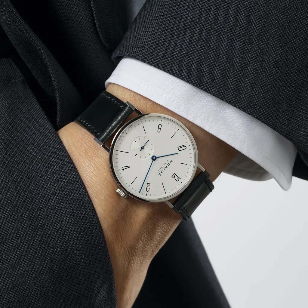 Man wearing NOMOS Glashütte Tangente 38mm watch with white dial, stainless steel case, and black leather strap