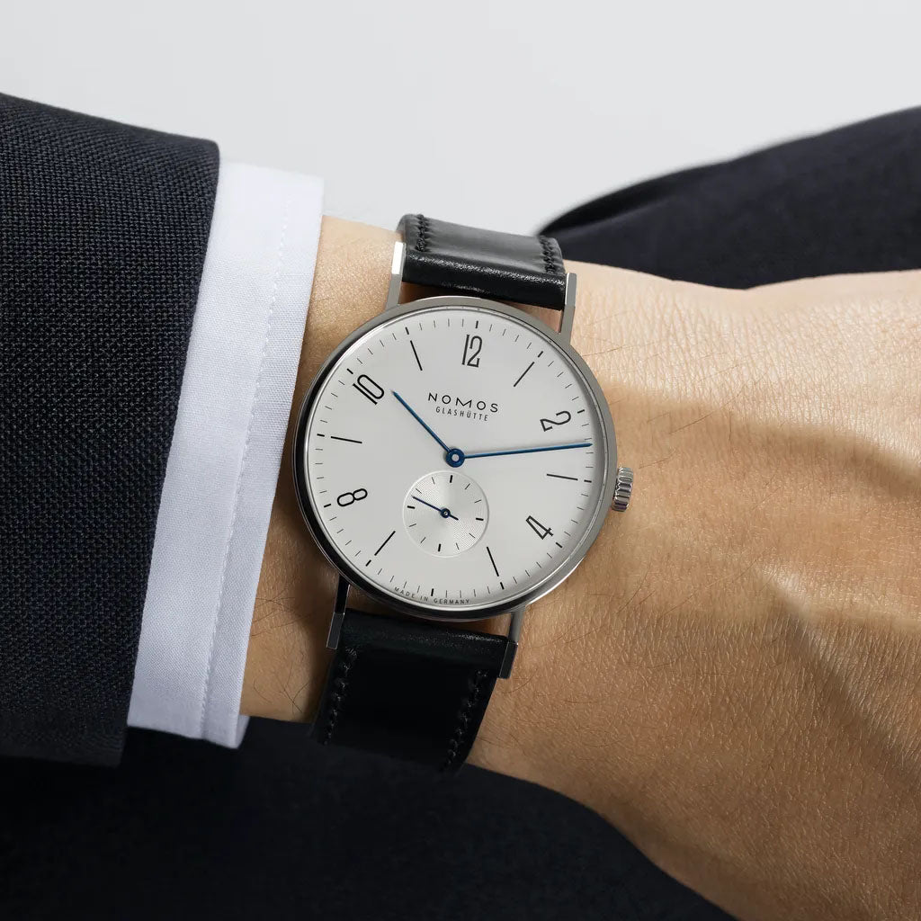 Man wearing NOMOS Glashütte Tangente 38mm watch with white dial, stainless steel case, and black leather strap