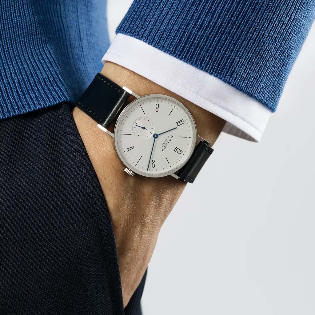 Man wearing NOMOS Glashütte Tangente 38mm watch with white dial, stainless steel case, and black leather strap