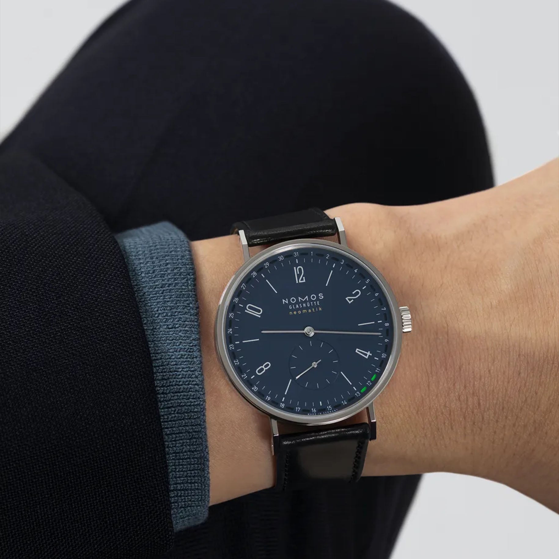 Man wearing NOMOS Glashütte Tangente Neomatik 41mm watch with midnight blue dial, stainless steel case, and black leather strap