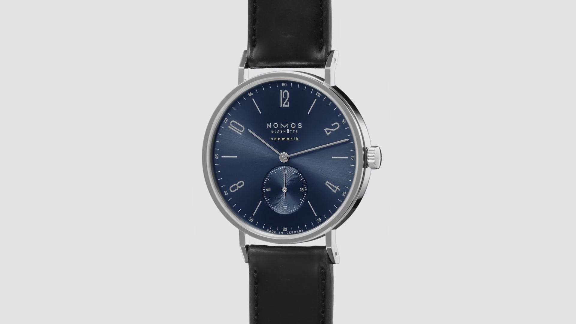 NOMOS Glashütte Tangente Neomatik Blue Gold 39mm automatic watch with blue sunburst dial, stainless steel case, and black leather strap on grey background, 360 spin.