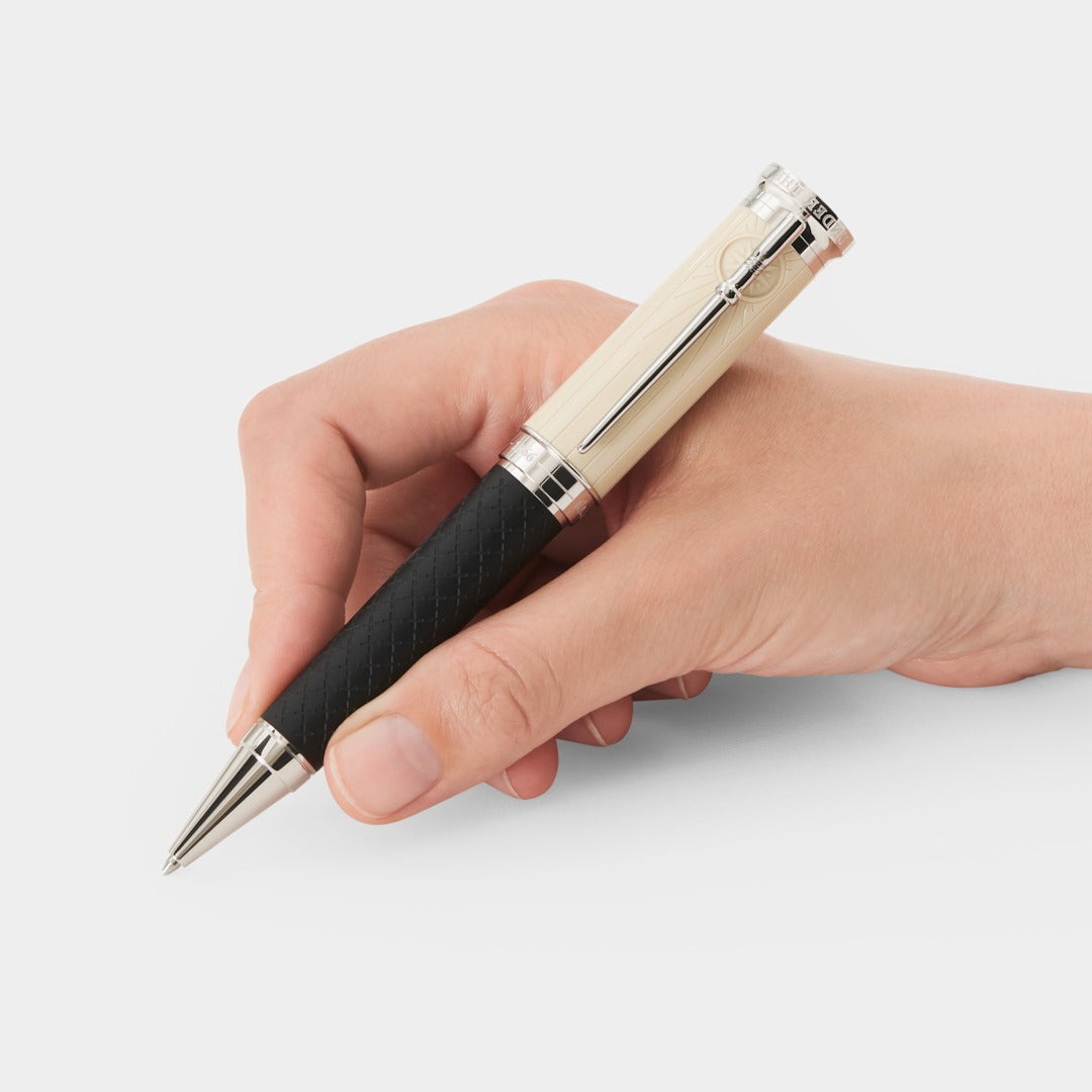 Hand holding a pen with a black and silver design on a white background