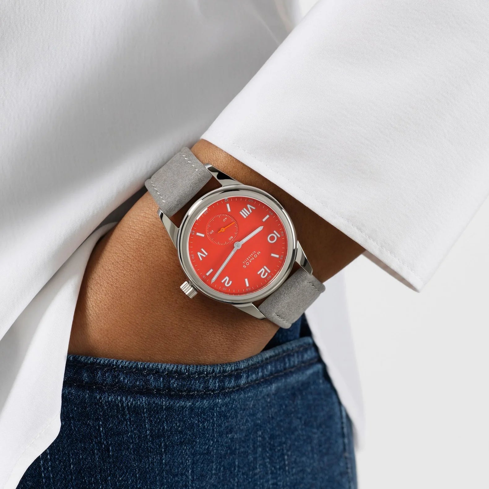 Woman wearing NOMOS Glashütte Club Campus 36mm watch with bold red dial, white luminous hands, and vegan velvet gray strap.
