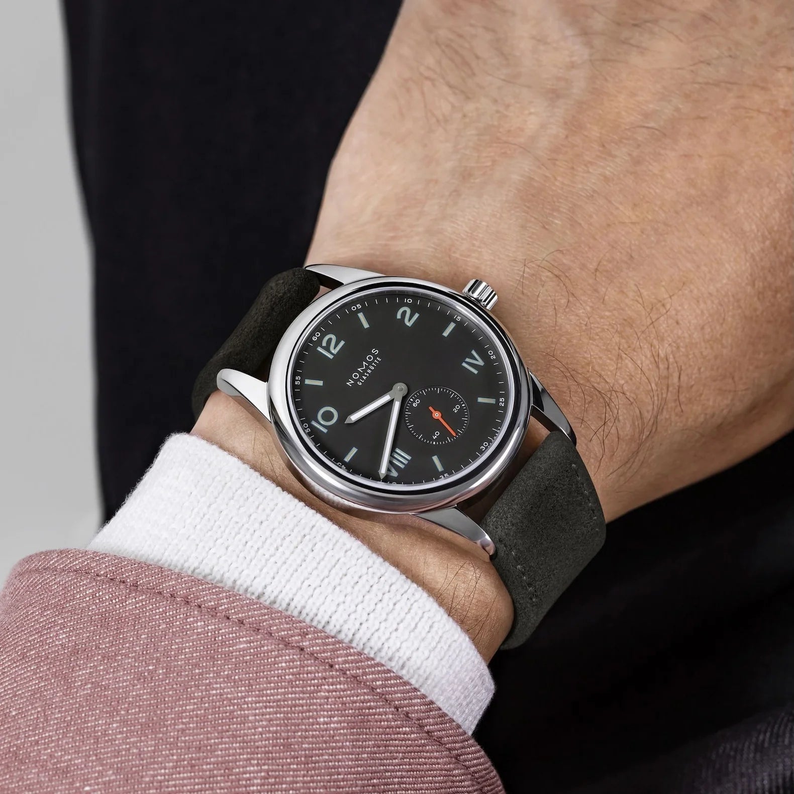 Man wearing NOMOS Glashütte Club Campus 38.5mm watch with dark ruthenium-plated dial, blue luminescent numerals, and vegan anthracite strap