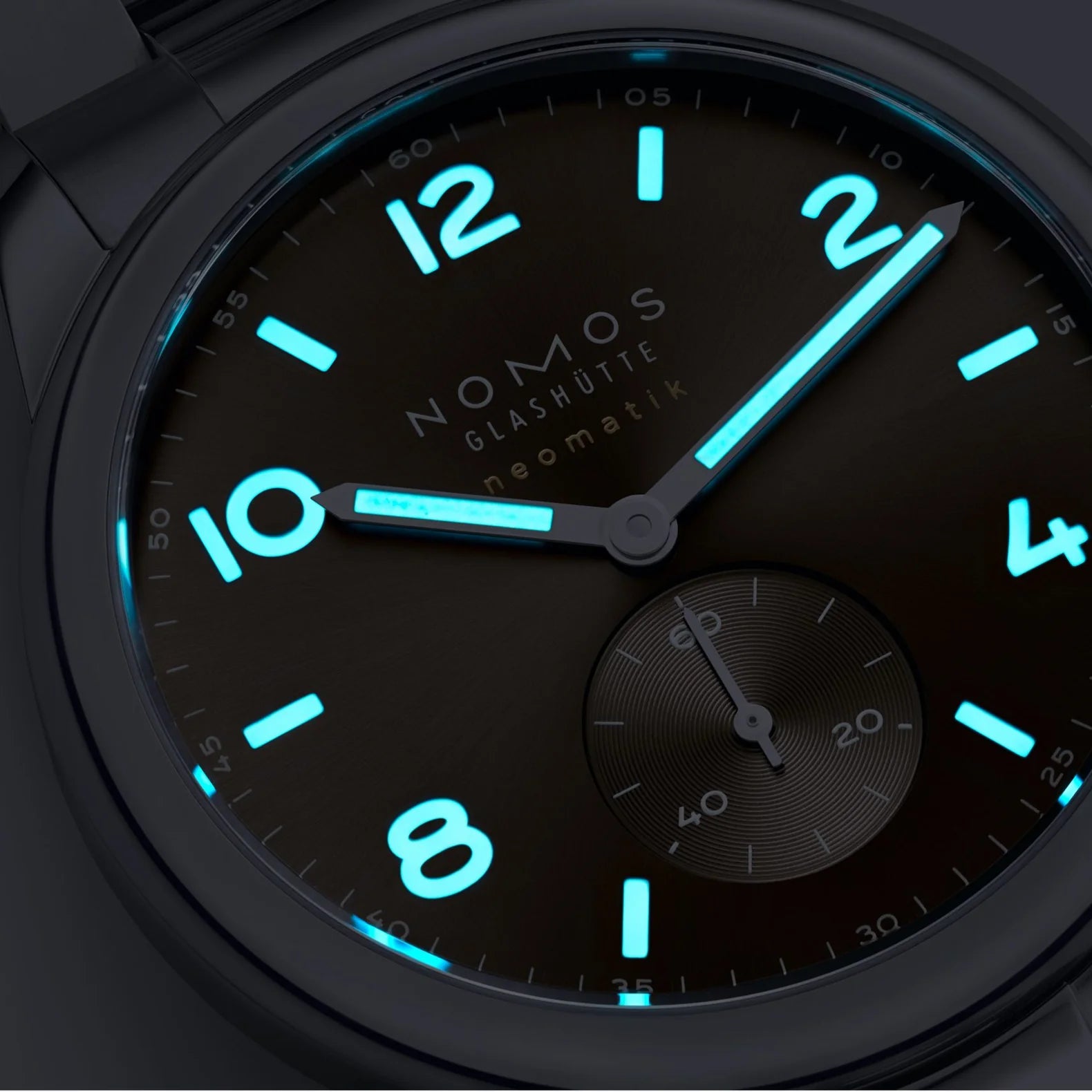 NOMOS watch with glowing blue numbers and hands on a dark background
