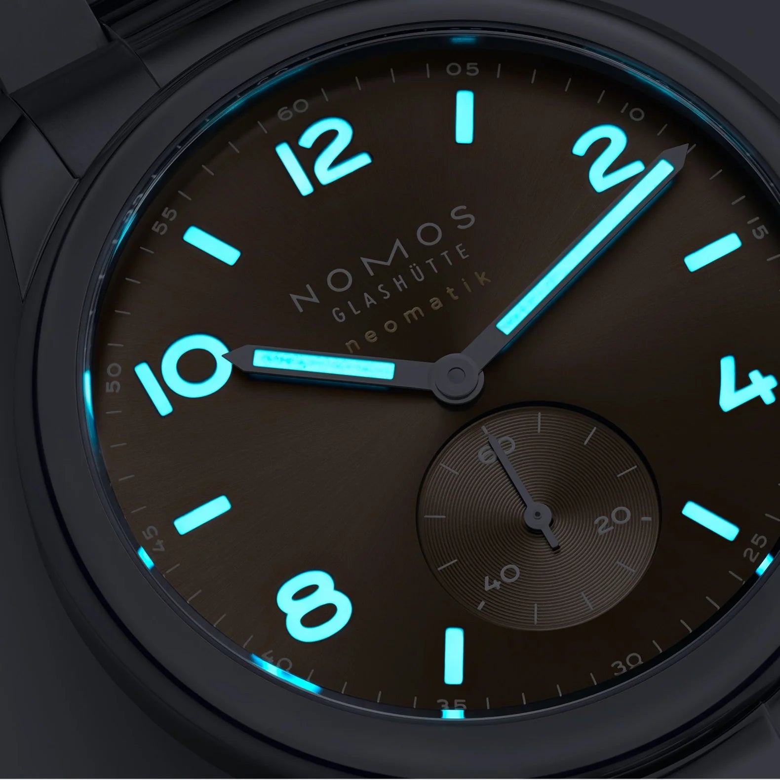 NOMOS watch with glowing blue numbers and hands on a dark background