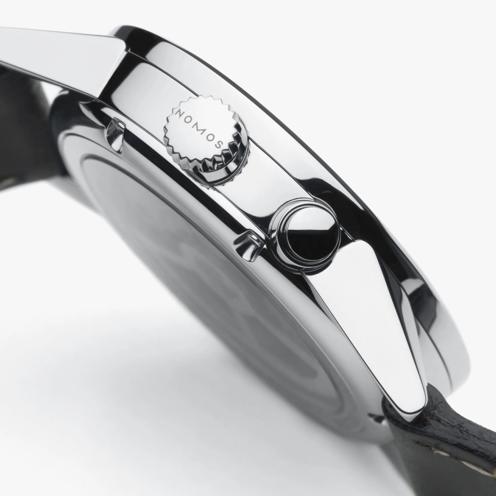 Close-up of a silver watch with 'Nomos' branding on a white background