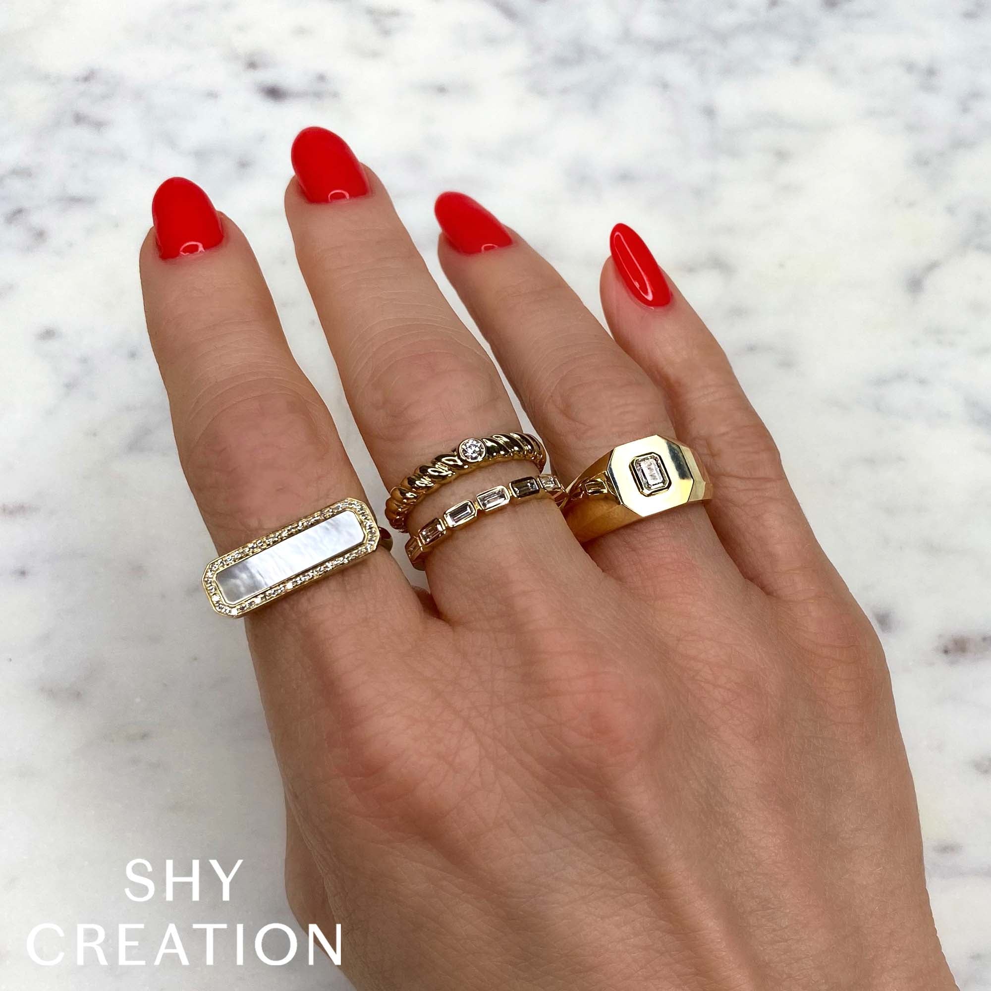 Woman's hand wearing yellow gold bezel set baguette diamond fashion ring