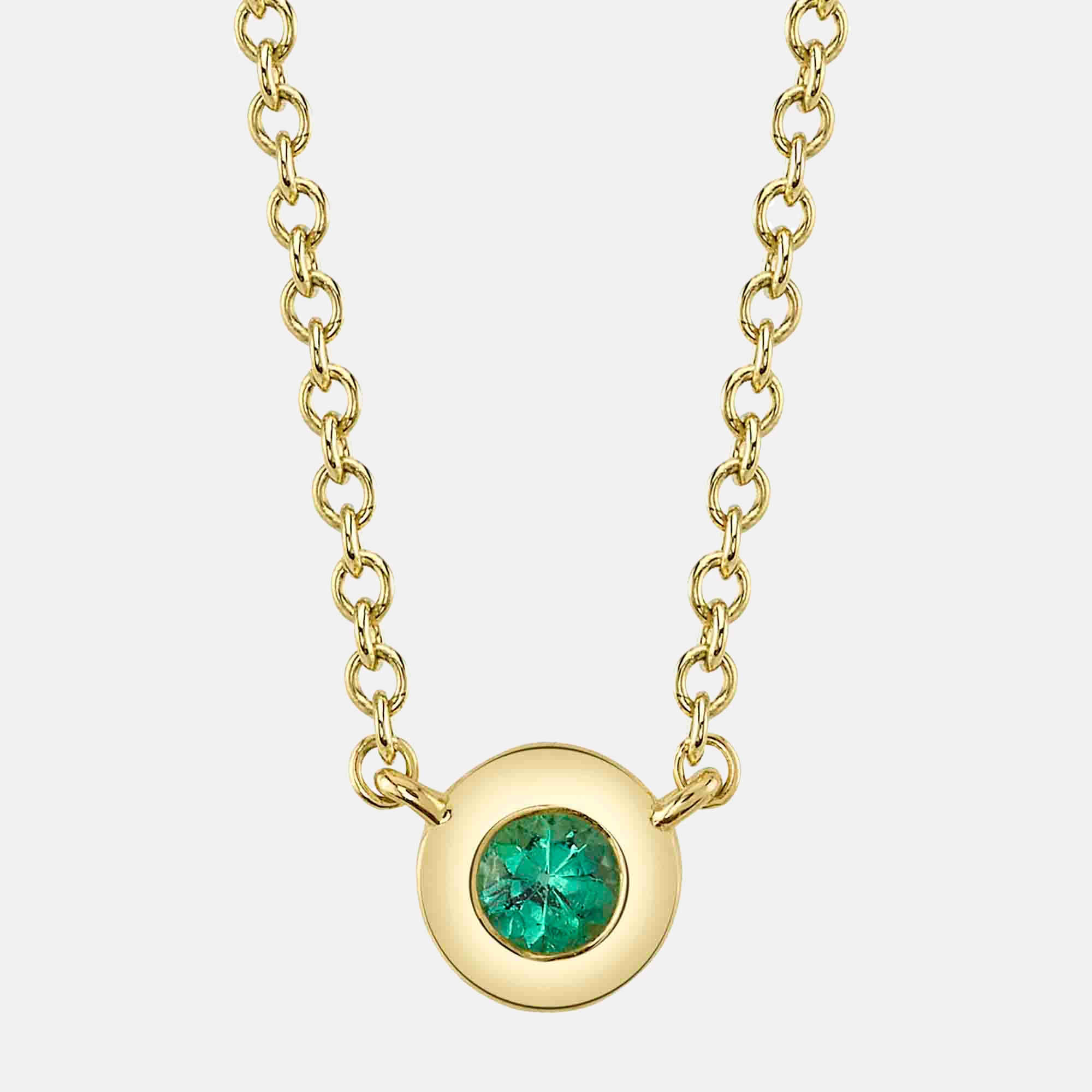 Gold necklace with a green emerald pendant on a white background