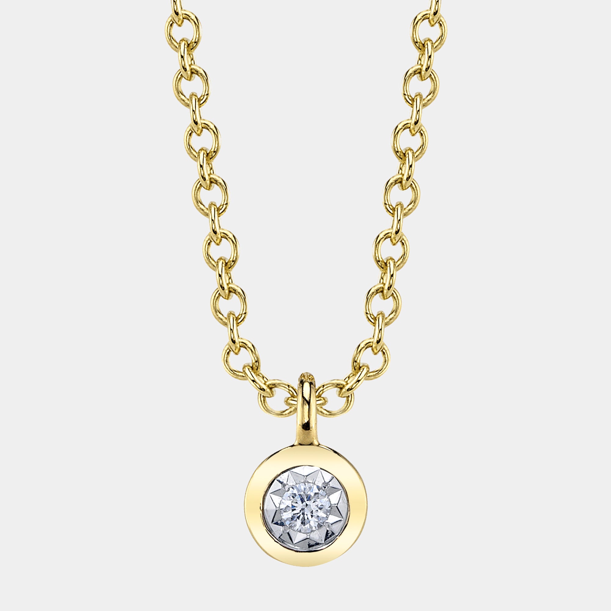 Gold necklace with a diamond pendant on a light gray background