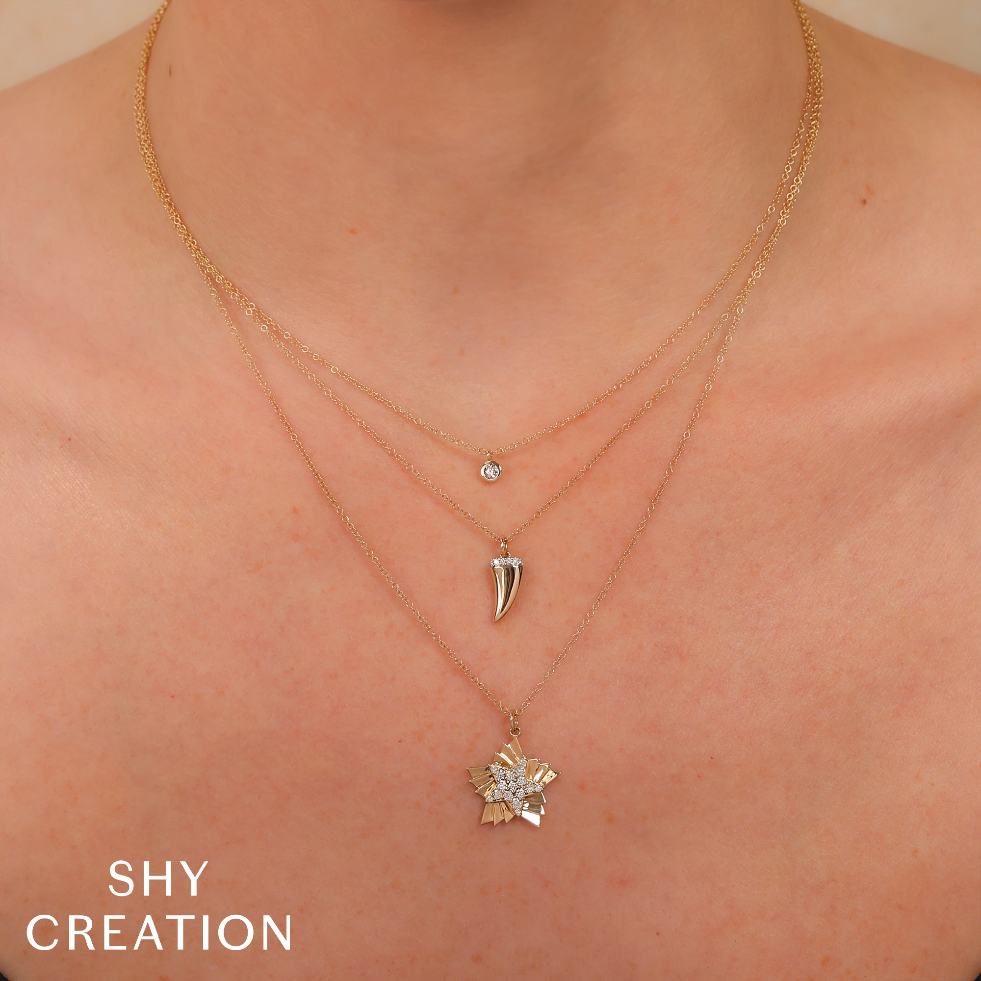 Close-up of layered gold necklaces with pendants on a person's neck