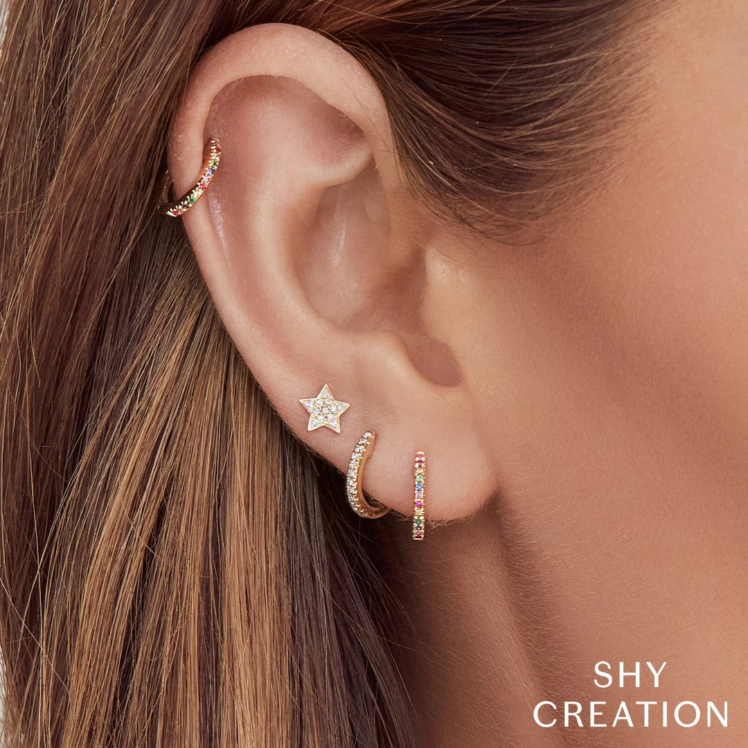 Woman wearing yellow gold diamond star stud earrings, closeup side angle of ear