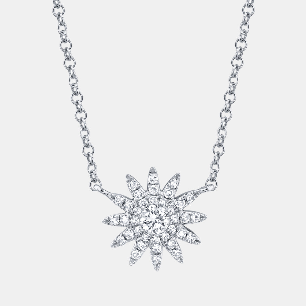White gold starburst diamond pendant necklace on a light gray background