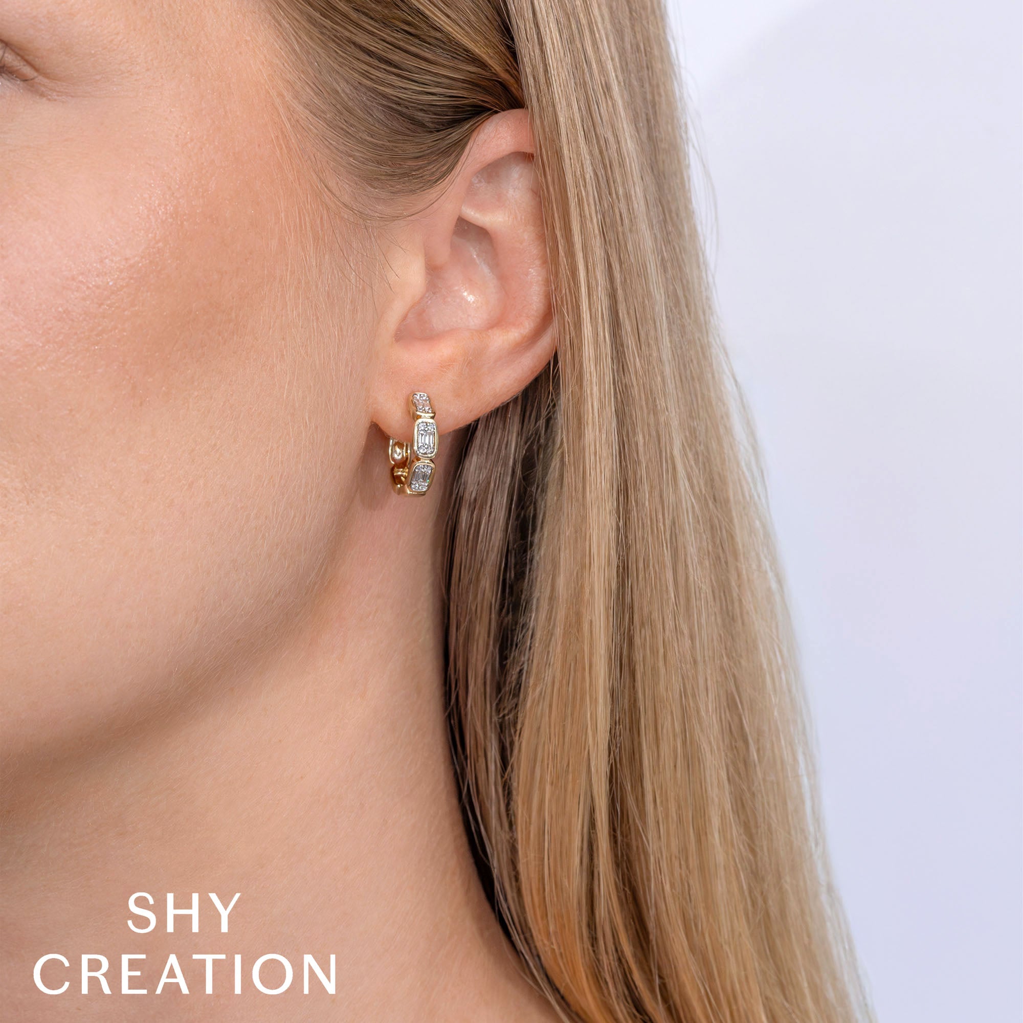 Woman wearing yellow gold baguette diamond hoop earrings