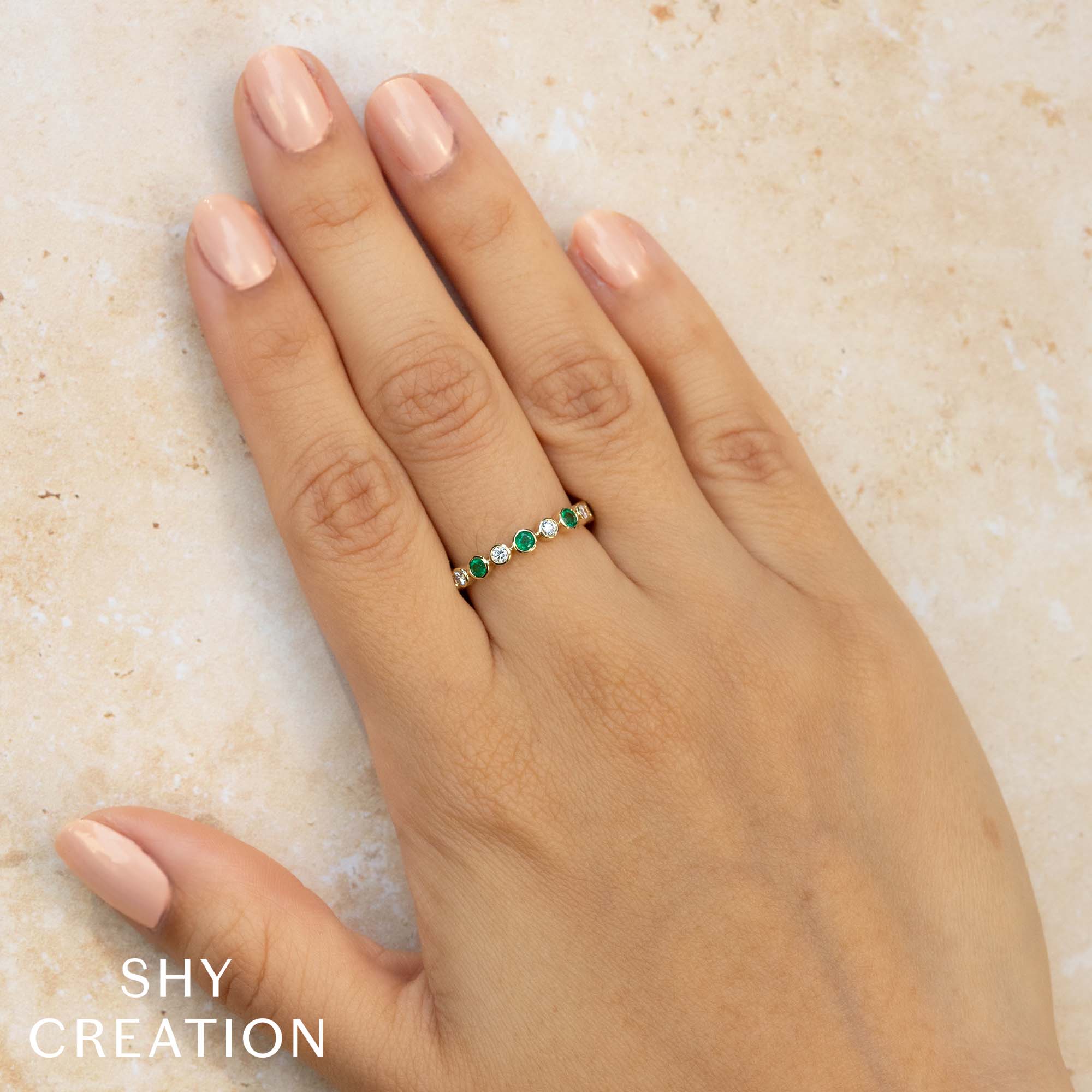 Woman wearing yellow gold emerald and diamond fashion ring