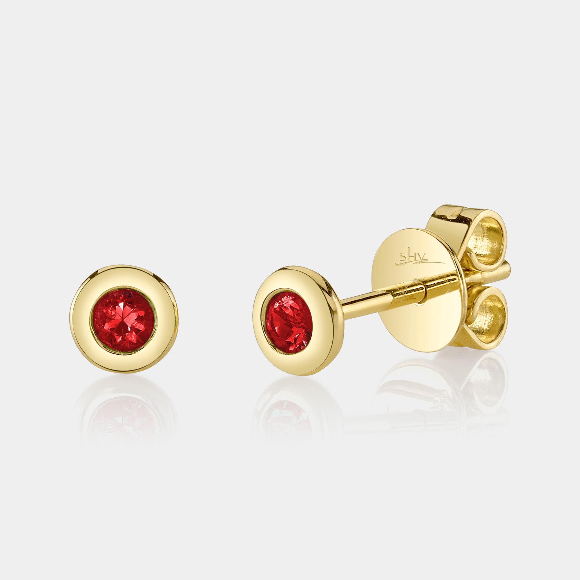 Yellow gold bezel set ruby stud earrings, front angle view