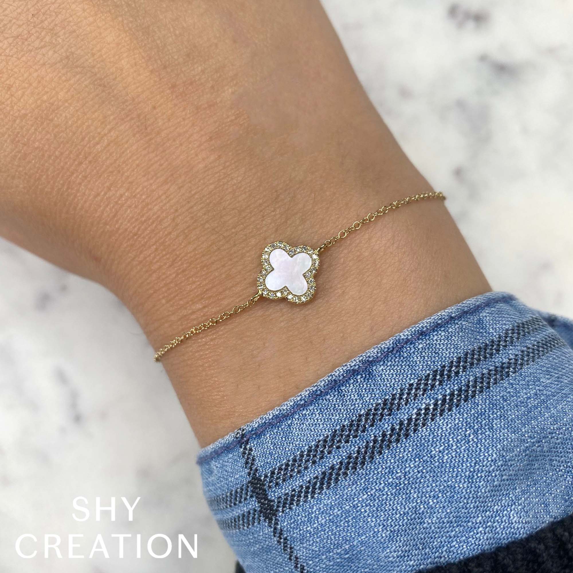 Woman wearing yellow gold diamond clover pendant bracelet, close-up wrist