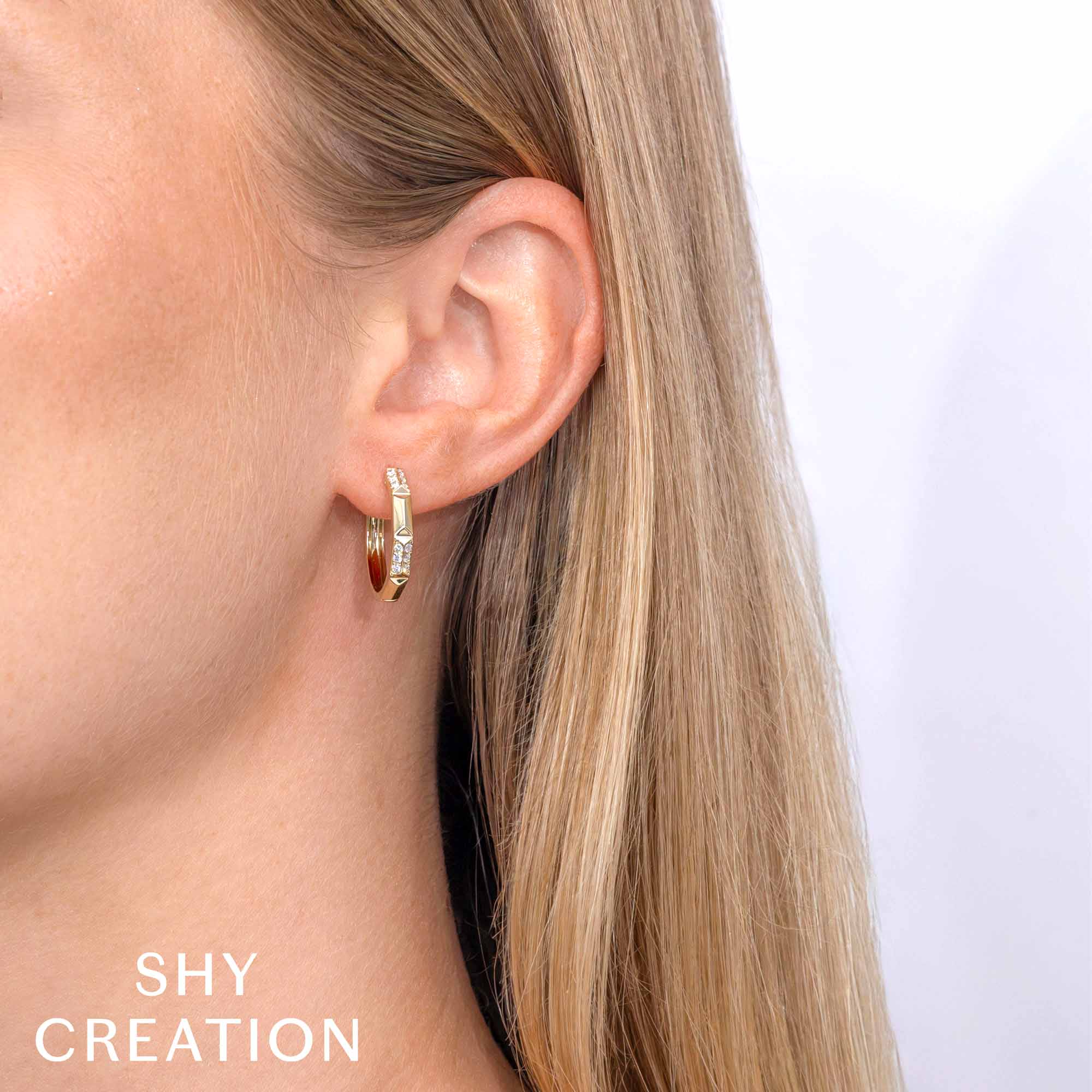 Woman wearing yellow gold geo cut diamond huggie earrings