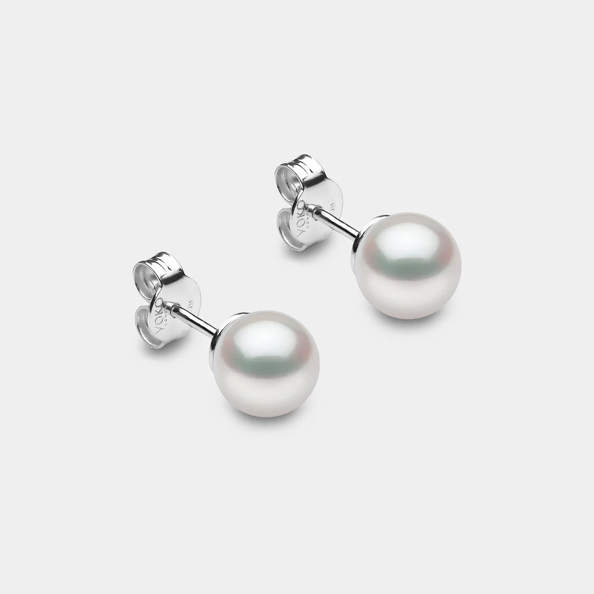 White gold classic pearl earrings on grey background, side angle view