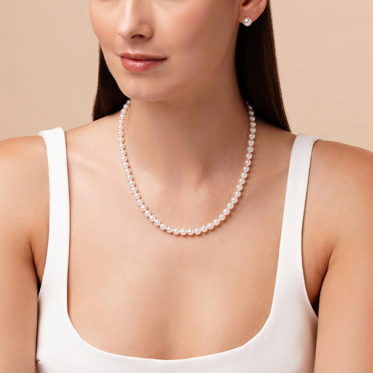 Woman wearing a pearl necklace against a beige background