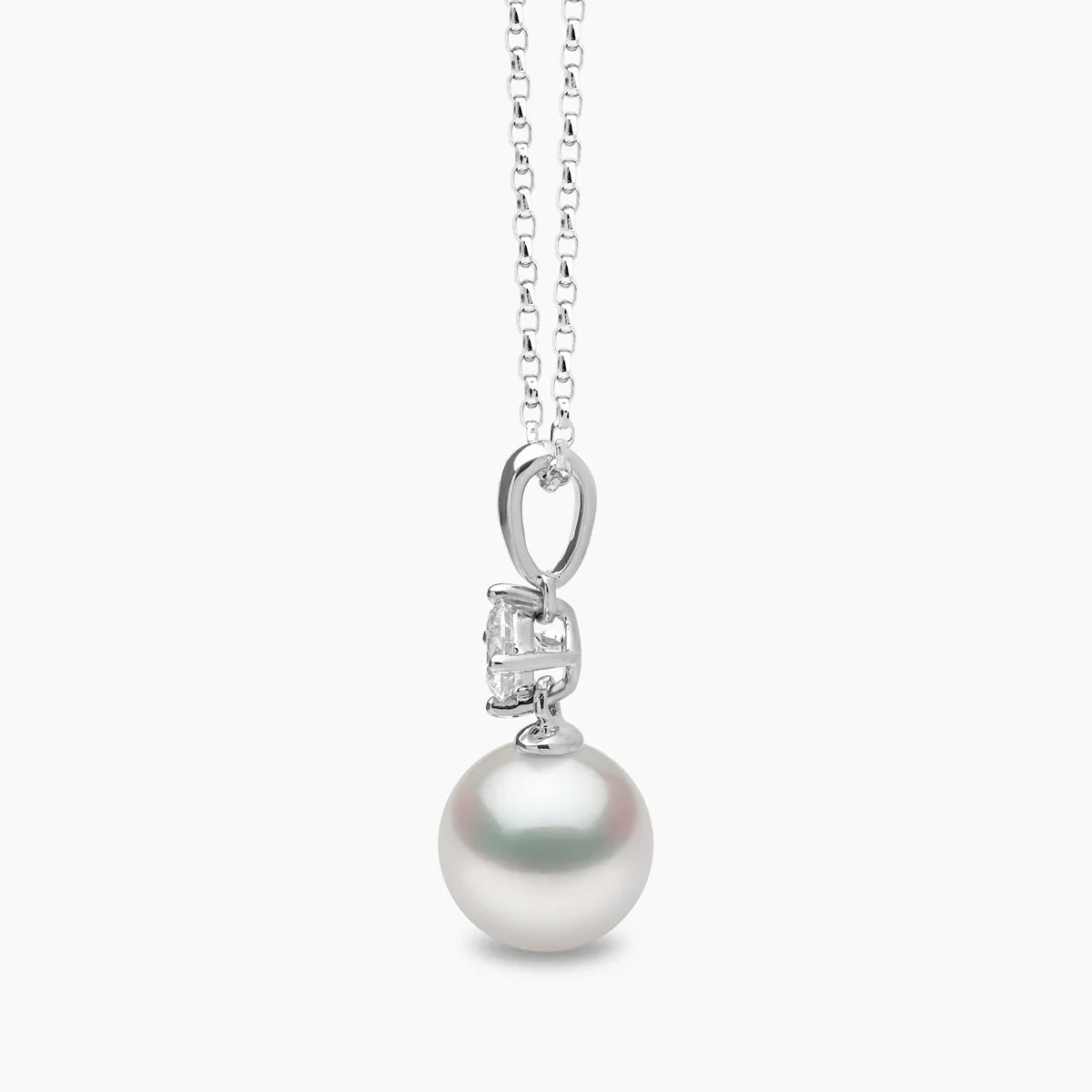 White gold pearl pedant necklace with solitaire diamond accent on grey background, side view