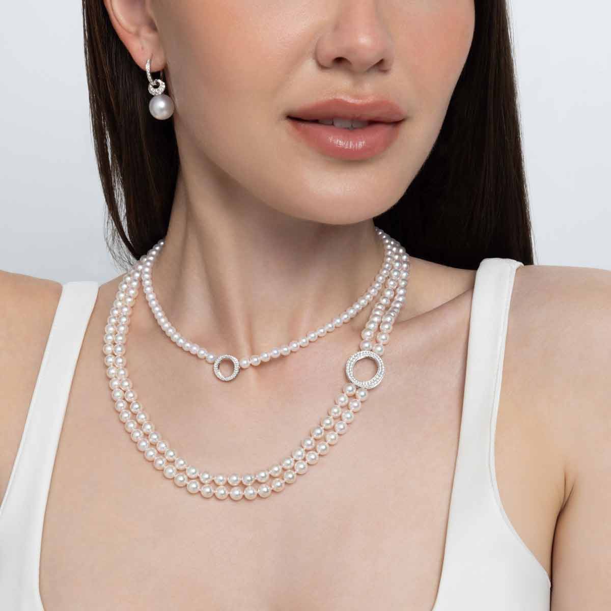 Woman wearing a pearl necklace and earrings on a white background