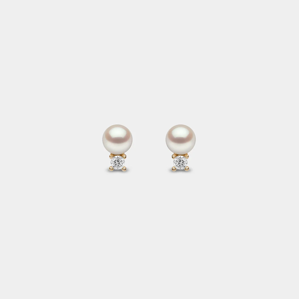White pearl stud earrings with diamond accents, front view