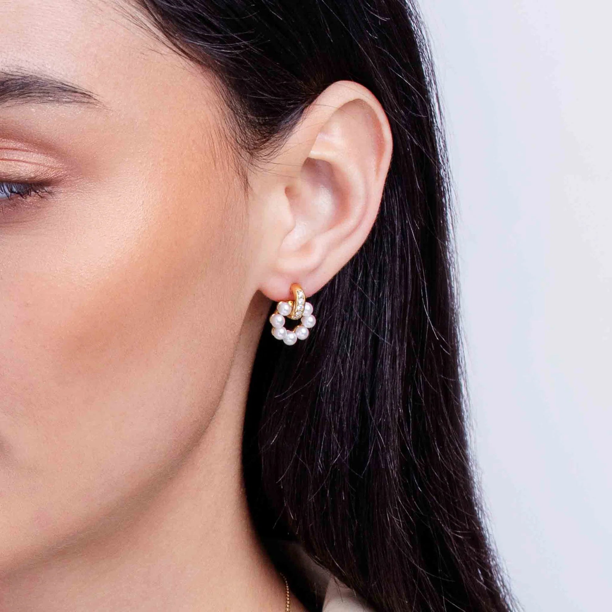 Woman wearing yellow gold pearl and diamond stud earrings